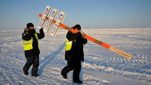 Сотрудники дрейфующей ледовой базы Барнео, находящейся в Арктике, несут символический столб, обозначающий Северный полюс. Архивное фото